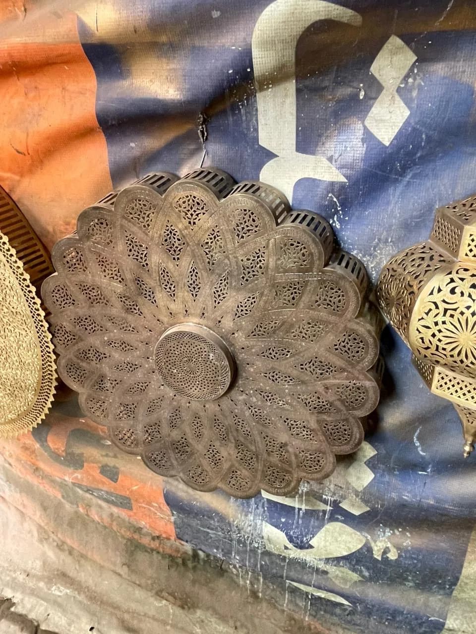 A scalloped rosette of pierced, darkened brass, each petal cut with a different lattice
